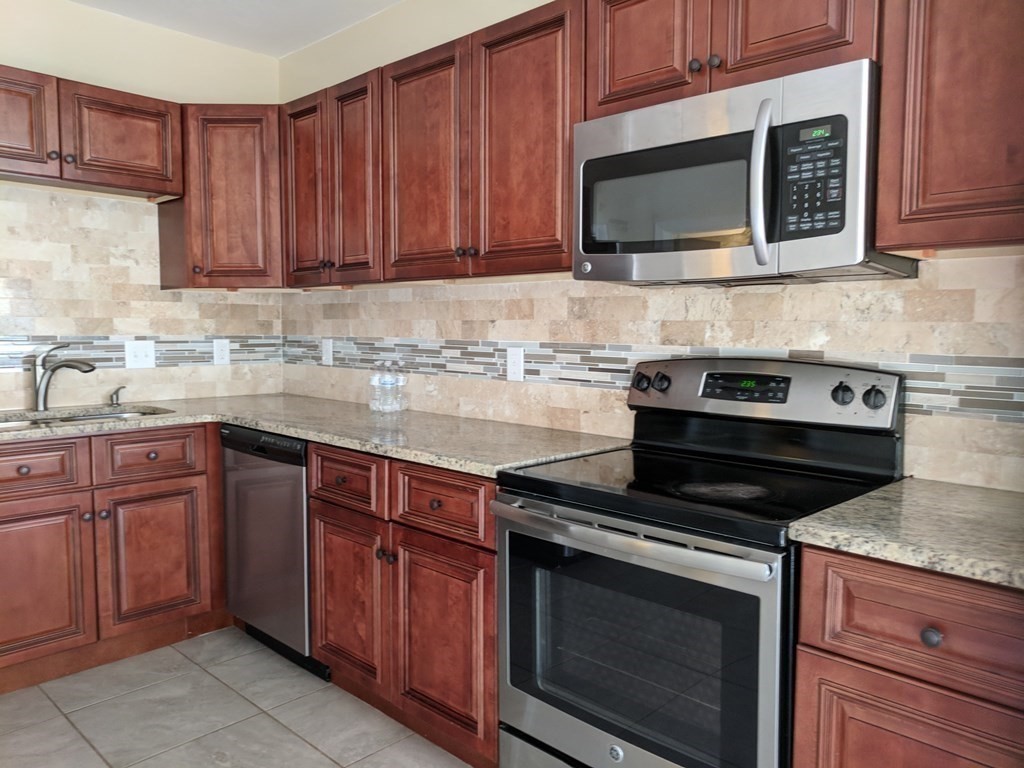 121 Winfield Street Worcester, MA 01602 - Photo 7 of 42 a kitchen with granite countertop wood cabinets and stainless steel appliances