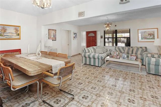 a living room with furniture a flat screen tv and a refrigerator