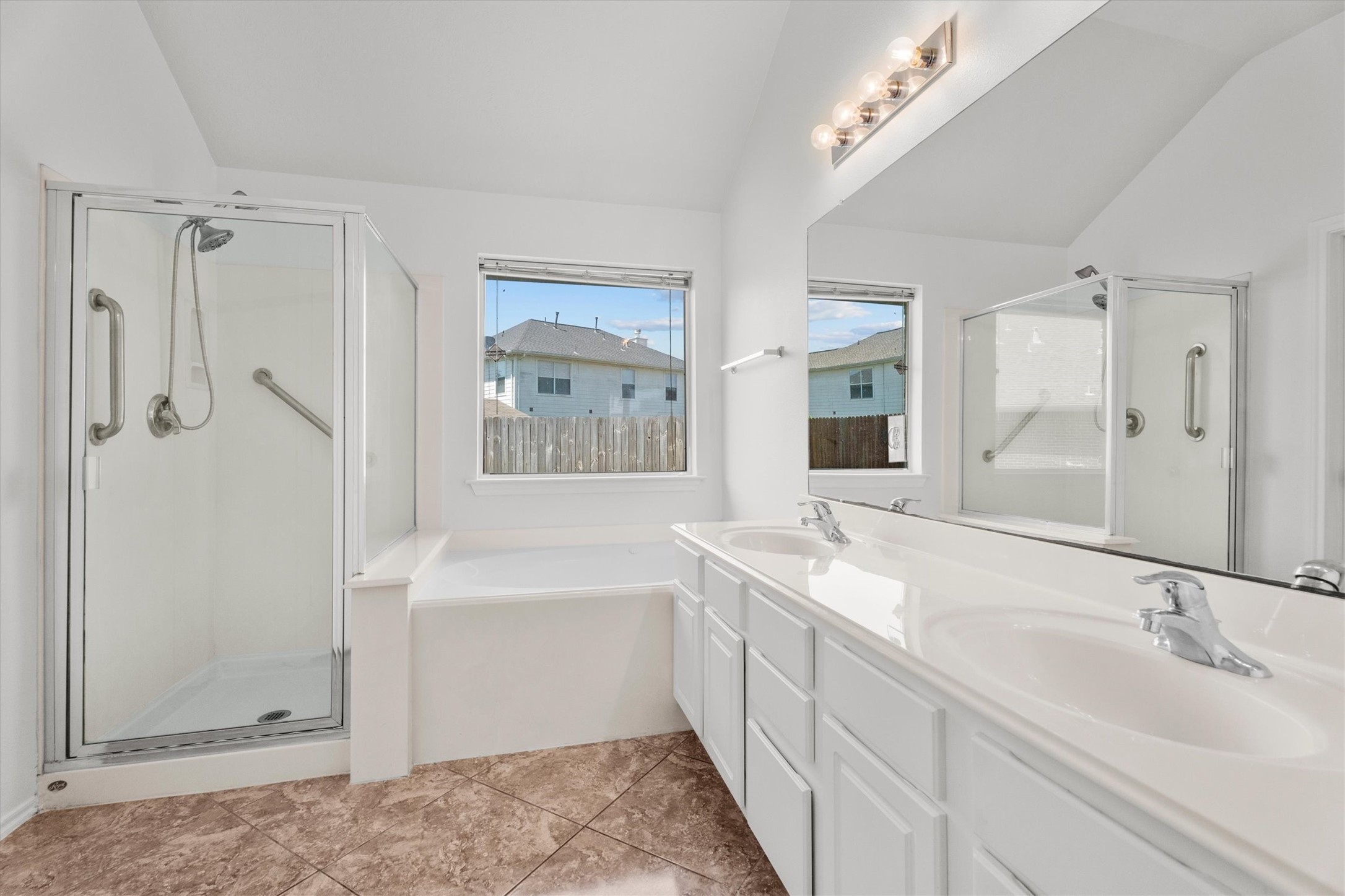 2507 Grayfeather Court Spring, TX 77388 - Photo 17 of 37 Primary bathroom featuring a spacious layout with dual sinks, a large mirror, a glass-enclosed shower, and a separate bathtub. Natural light fills the room through two windows, highlighting the clean, modern design and tiled flooring.