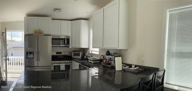 a kitchen with a refrigerator a stove a sink and white cabinets