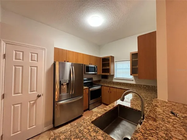 a kitchen with stainless steel appliances granite countertop a refrigerator sink and stove