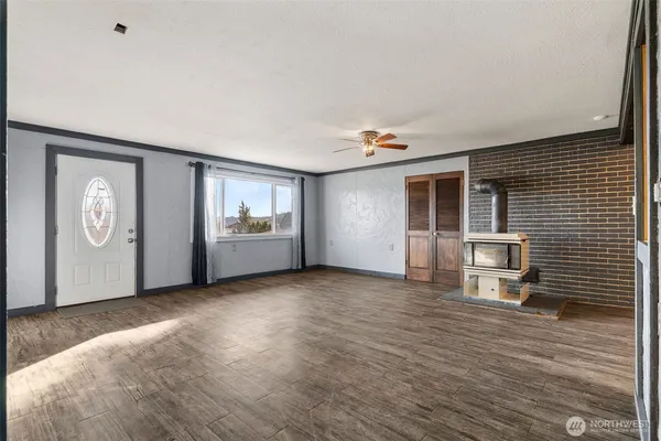 a view of an empty room with a window and wooden floor