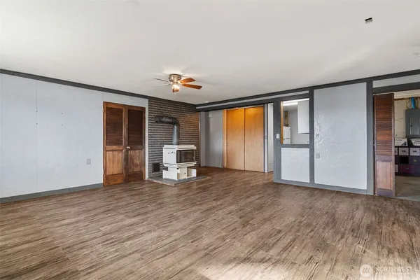 a view of an empty room with a window and wooden floor