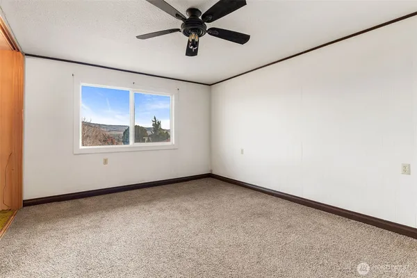 an empty room with windows and fan