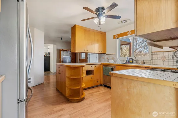 a kitchen with stainless steel appliances granite countertop a refrigerator a sink dishwasher a stove and a dining table with wooden floor