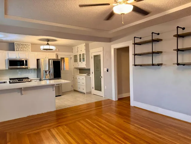 a large white kitchen with stainless steel appliances granite countertop a stove and a refrigerator