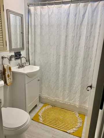 a bathroom with a sink a toilet and shower curtain