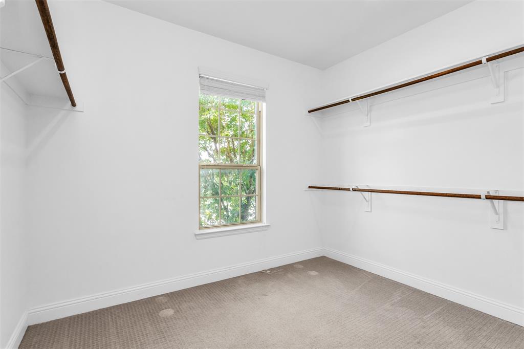6333 Hall Road Frisco, TX 75034 - Photo 23 of 38 Spacious closet featuring multiple wood-finish hanging rods, white shelving, a window with natural light, and neutral carpeting