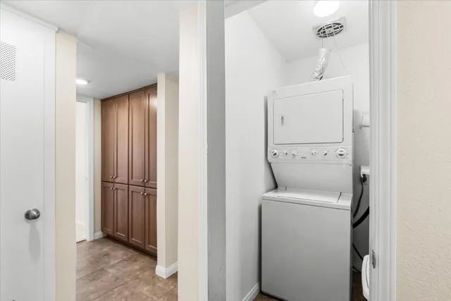 an empty room with chandelier fan and windows