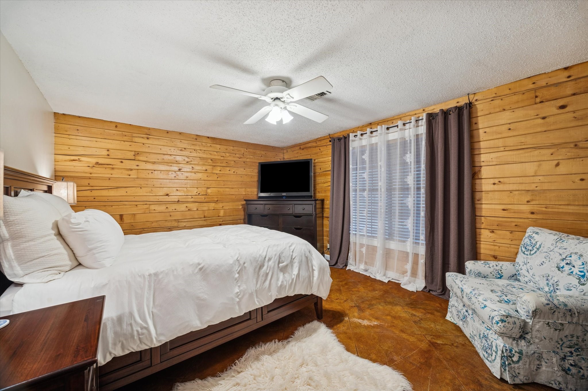 21538 Mueschke Road Tomball, TX 77377 - Photo 41 of 50 The primary bedroom offers a tranquil escape with wood-paneled walls, soft natural light, and space for relaxation. Upstairs, the additional bedrooms feature warm wood floors, charming architectural details, and plenty of room for guests.