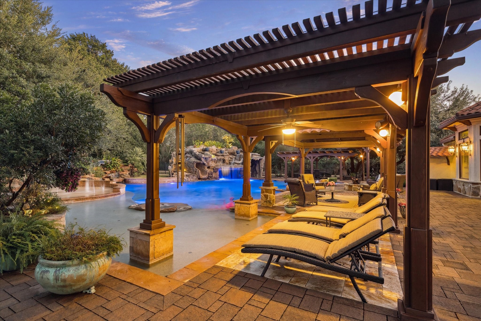 21538 Mueschke Road Tomball, TX 77377 - Photo 47 of 50 Resort-style relaxation under elegant pergolas! This outdoor retreat features a sparkling pool with rock waterfalls, integrated spa, and lush landscaping. Multiple shaded lounging areas and a covered cabana create the perfect setting for entertaining or unwinding in luxury.