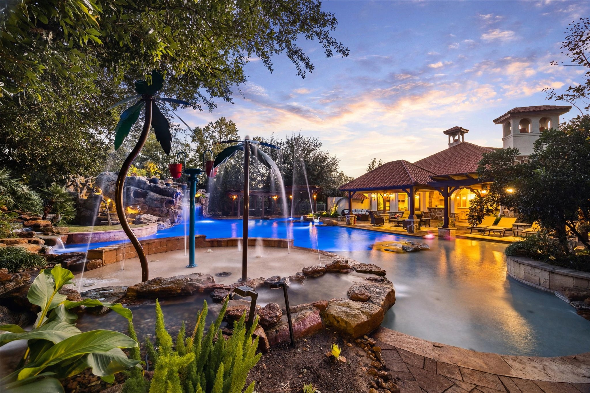 21538 Mueschke Road Tomball, TX 77377 - Photo 48 of 50 Private oasis with water features and lush landscaping! This incredible outdoor space includes a sparkling pool with rock waterfalls, integrated spa, and playful splash elements—perfect for family fun or entertaining. The covered cabana and seating areas provide comfort and elegance for gatherings day or night.