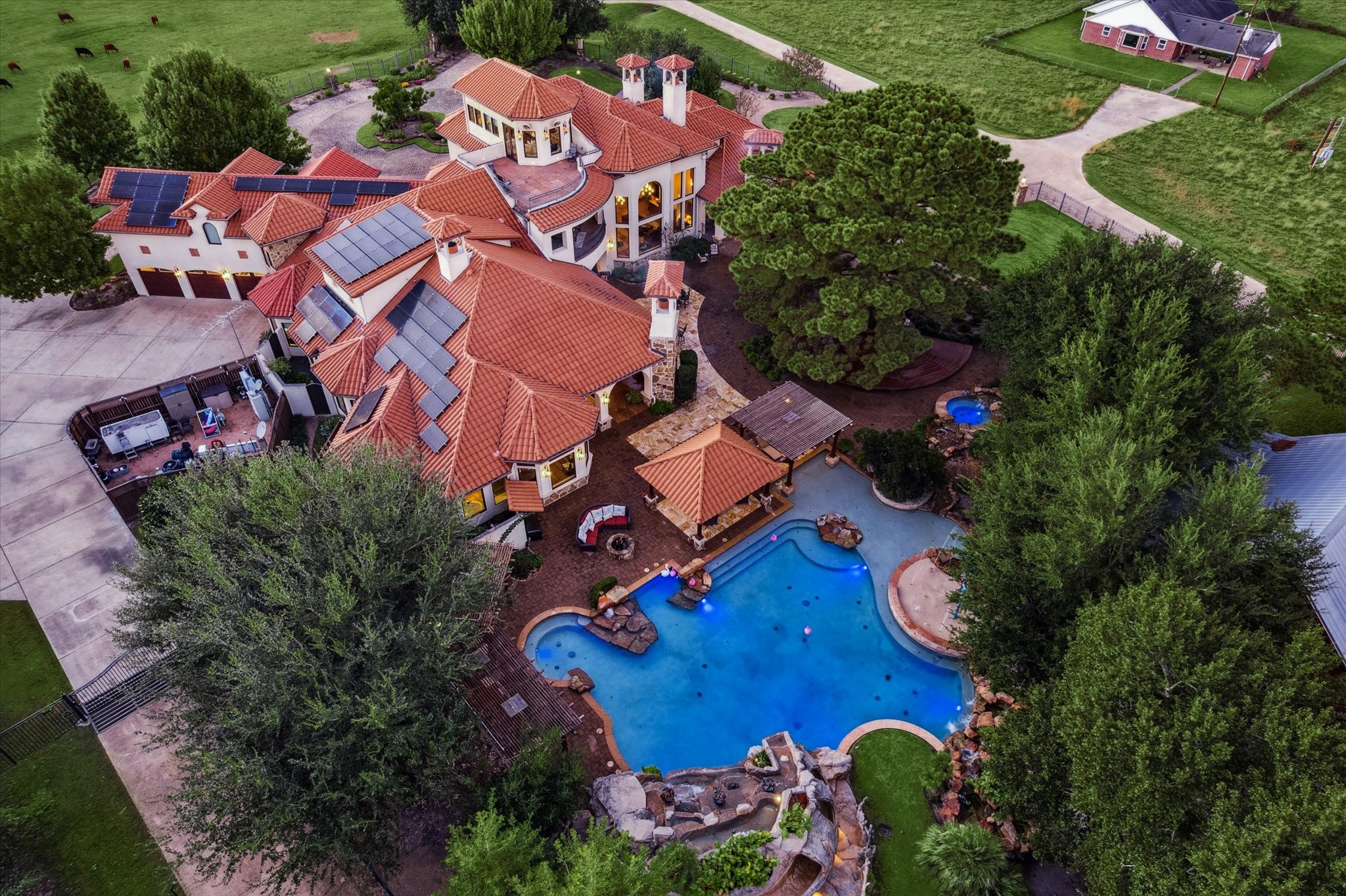 21538 Mueschke Road Tomball, TX 77377 - Photo 50 of 50 Resort-style luxury at its finest! This Mediterranean estate features a spectacular waterpark-inspired pool with rock waterfalls, integrated spa, and swim-up seating. A covered outdoor kitchen and cabana make entertaining effortless, while solar panels add energy efficiency. Surrounded by lush landscaping and expansive acreage, this property offers unmatched privacy and space.