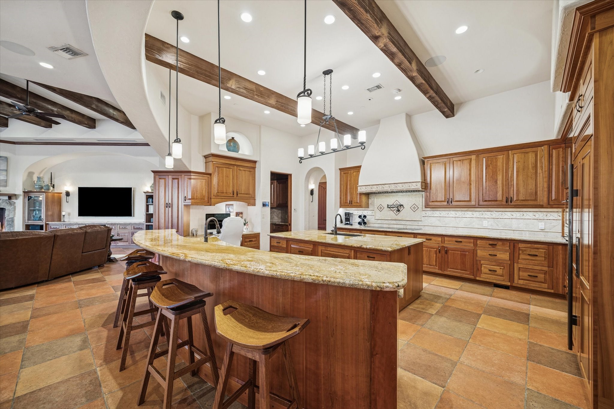 21538 Mueschke Road Tomball, TX 77377 - Photo 8 of 50 A true culinary masterpiece. This expansive kitchen seamlessly connects the living and family room spaces, ideal for entertaining and everyday living. Featuring two grand islands with full-size sinks and dual dishwashers, a spacious Sub-Zero refrigerator, a curved towering vent hood, an oversized induction cooktop with six burners plus two additional electric burners, a pot filler, and double Wolf convection ovens, this kitchen is outfitted with the finest appliances, combining style and functionality.