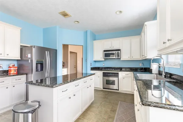 a kitchen with granite countertop a stove sink and refrigerator