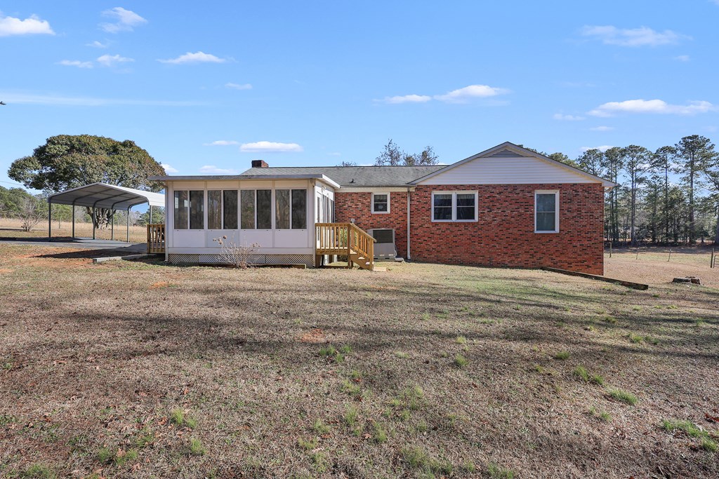 This residence features a carport, a sunroom, and a large yard perfect for outdoor enjoyment.