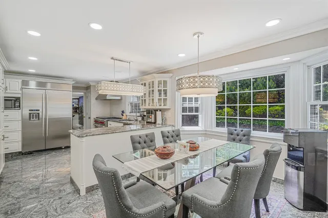 a kitchen with stainless steel appliances kitchen island granite countertop a dining table chairs and refrigerator