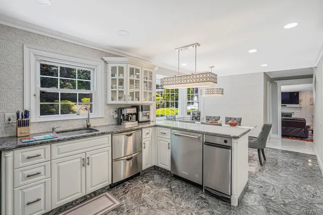 a kitchen with kitchen island granite countertop a sink and white cabinets