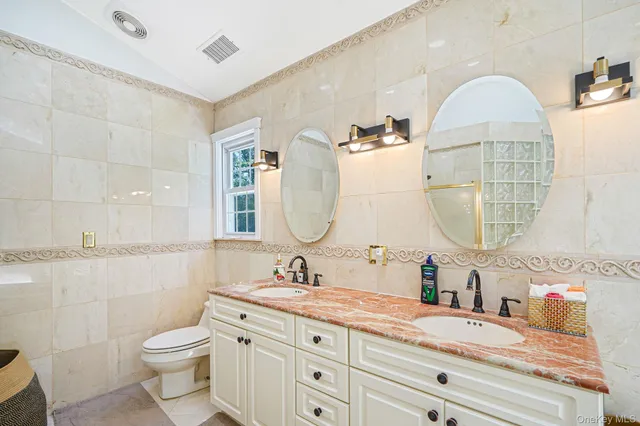a bathroom with a granite countertop toilet a sink and a mirror