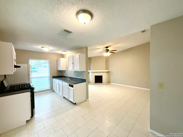 a large kitchen with a stove a sink dishwasher and a refrigerator with white cabinets