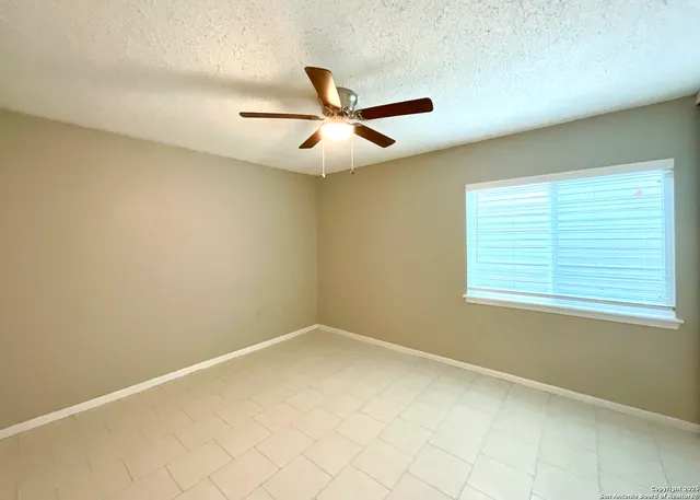 an empty room with a window and a fan