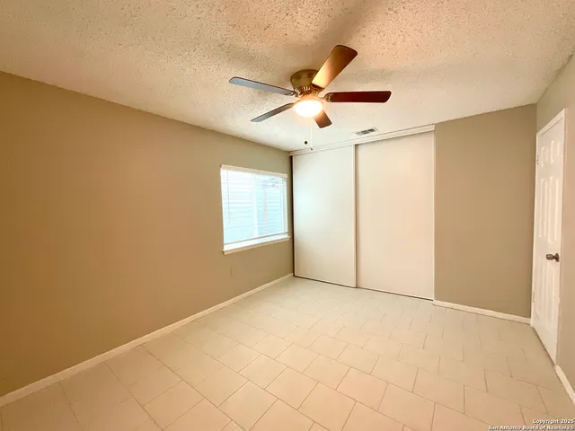 an empty room with windows and fan