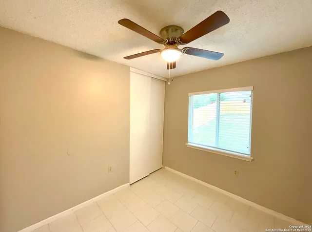 an empty room with windows and fan