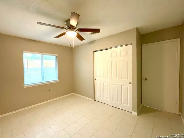 a view of an empty room with window and a chandelier fan