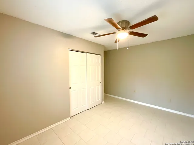 an empty room with ceiling fan and a window
