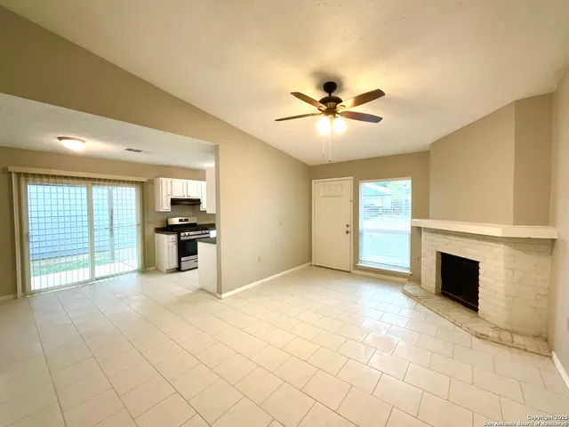 a view of an empty room with kitchen and window