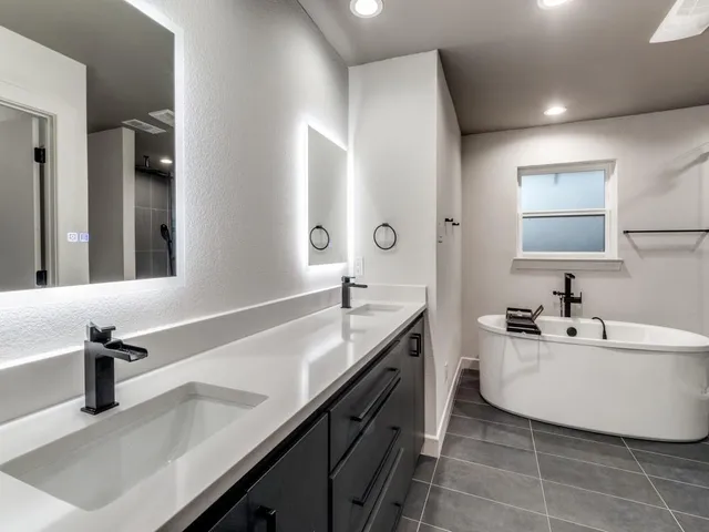 a spacious bathroom with a double vanity sink a mirror and a bathtub