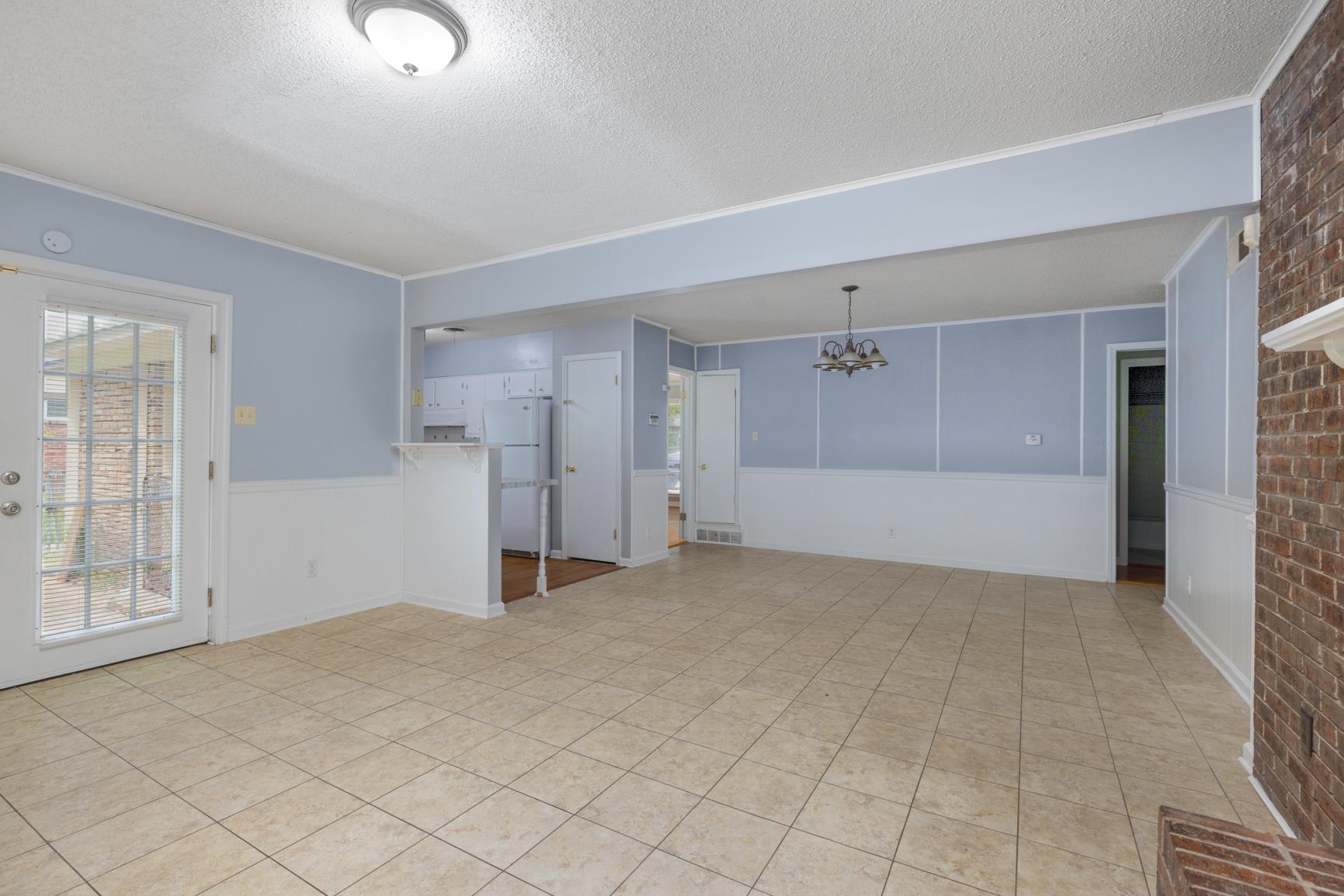 3853 Range Line Road Memphis, TN 38127 - Photo 7 of 18 Empty room featuring an inviting chandelier, a wainscoted wall, visible vents, and a textured ceiling