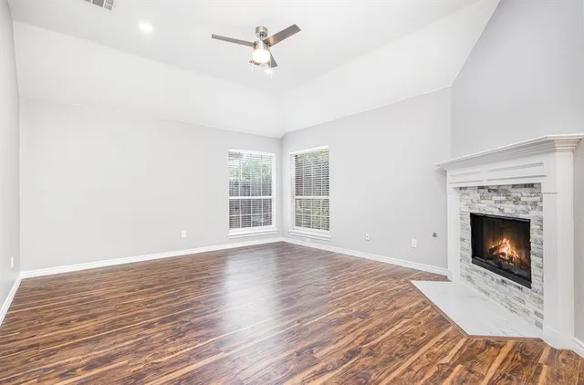 a view of an empty room with wooden floor fireplace and a window