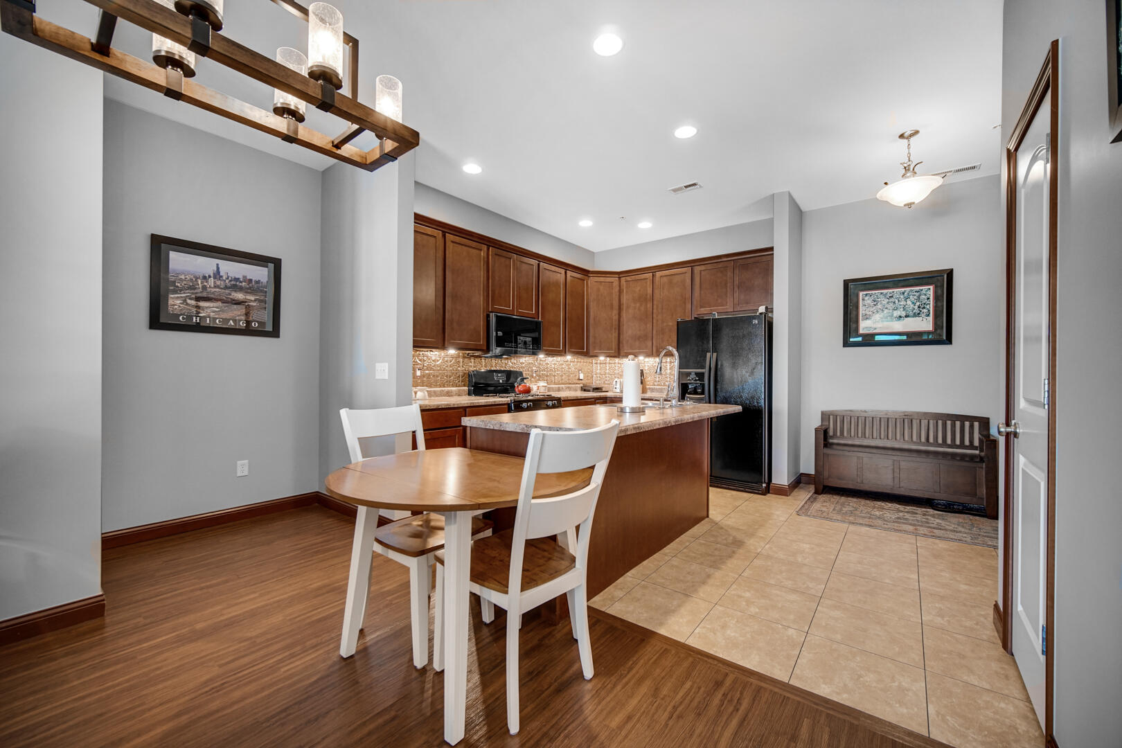 123 North Main Street, Unit 301 Crown Point, IN 46307 - Photo 10 of 25 a kitchen with stainless steel appliances kitchen island granite countertop a refrigerator a stove a microwave oven with a dining table and chairs with wooden floor