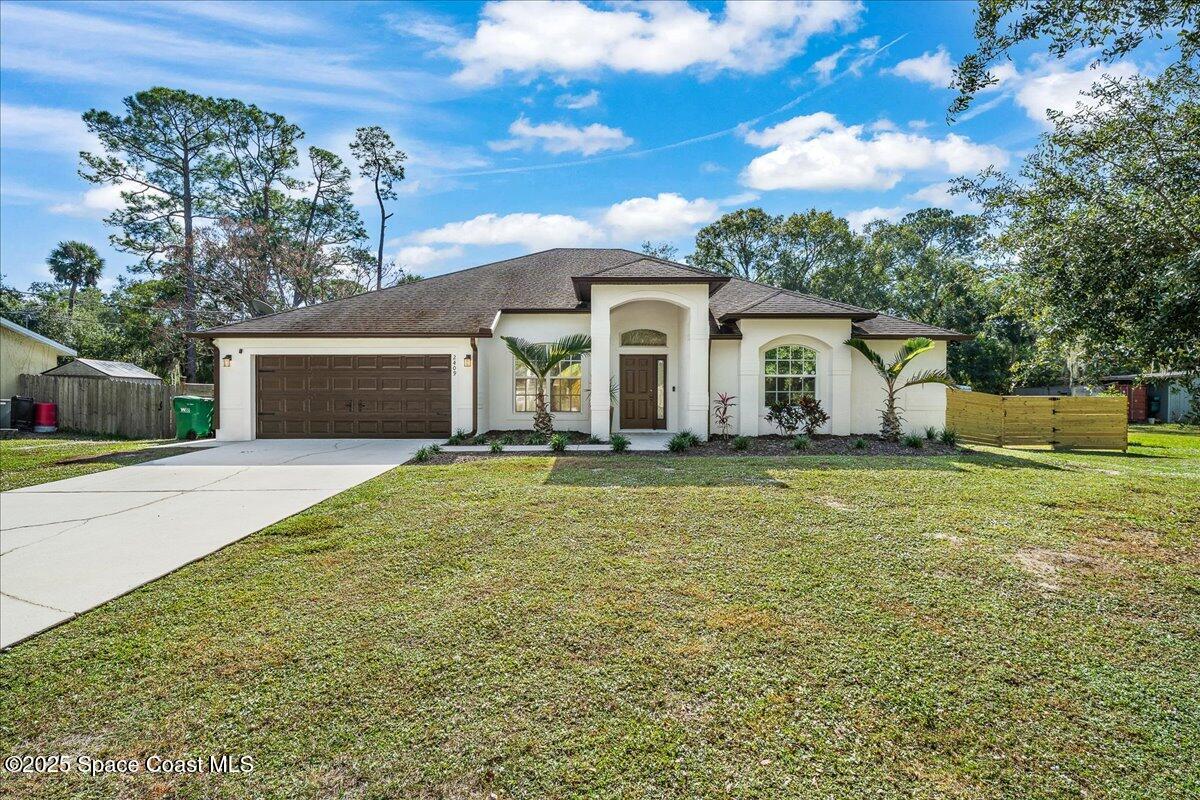 a view of a white house with a yard and large tree