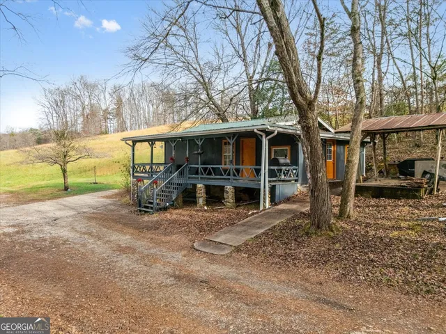 a view of a house with large tree next to a big yard