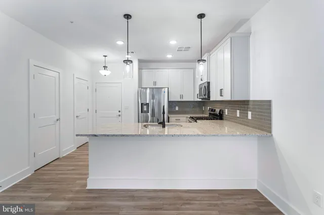 a large kitchen with granite countertop a sink a counter top space and cabinets