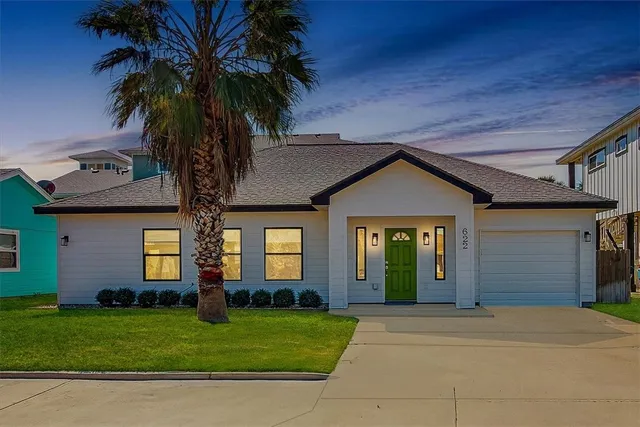 front view of a house with a yard and palm trees