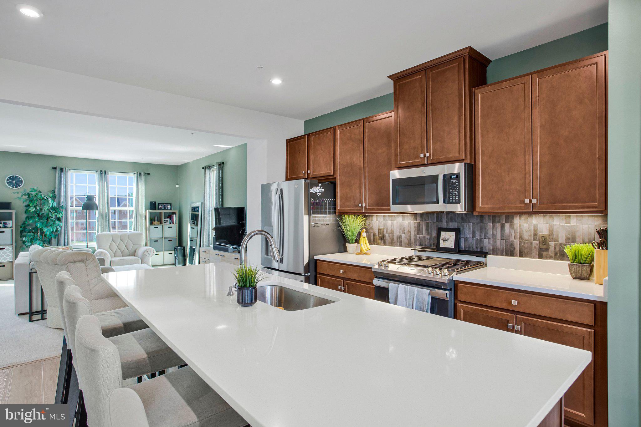 9012 Waller Tree Way Upper Marlboro, MD 20772 - Photo 6 of 29 a kitchen with stainless steel appliances a stove a sink a microwave a refrigerator a dining table and chairs
