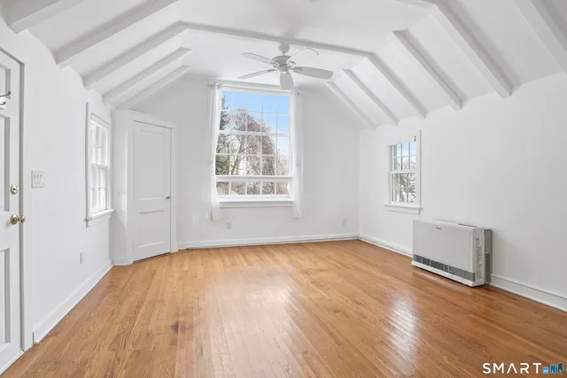 an empty room with wooden floor chandelier and windows