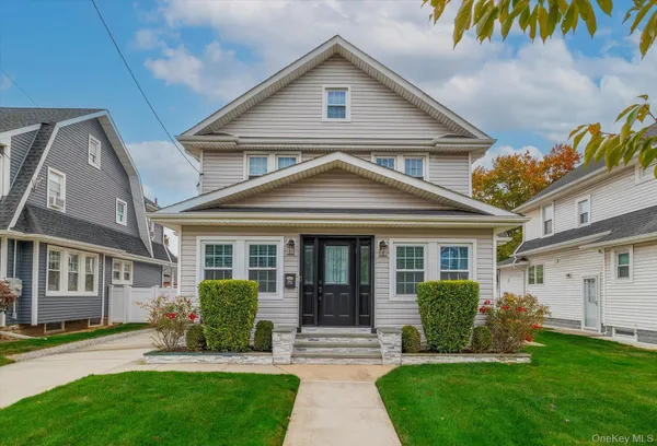 a front view of a house with a yard and potted plants