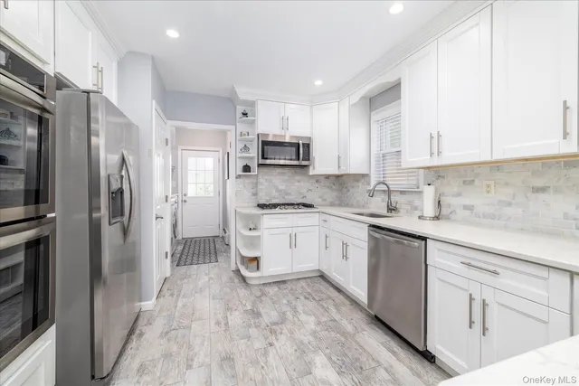 a kitchen with stainless steel appliances granite countertop a refrigerator sink and white cabinets