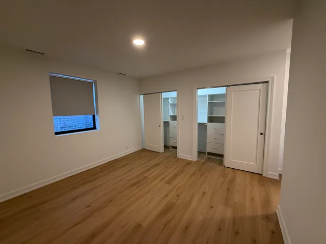 an empty room with wooden floor & closet and windows