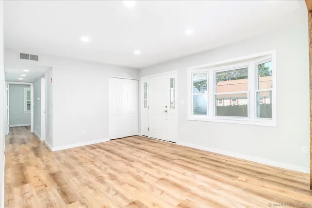 a view of an empty room with wooden floor and a window