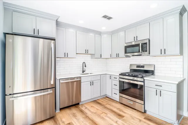 a kitchen with cabinets stainless steel appliances and wooden floor