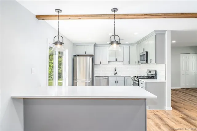 a kitchen with stainless steel appliances kitchen island a table chairs in it and wooden floors