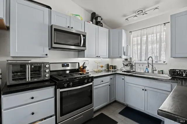 a kitchen with stainless steel appliances granite countertop white cabinets a sink a stove and a microwave