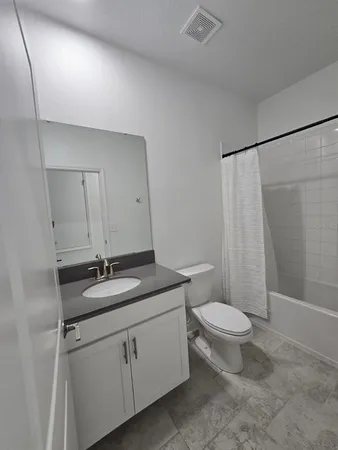 a bathroom with a granite countertop sink toilet a mirror and shower