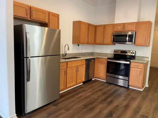 a kitchen with stainless steel appliances granite countertop a refrigerator stove a sink and dishwasher with wooden floor