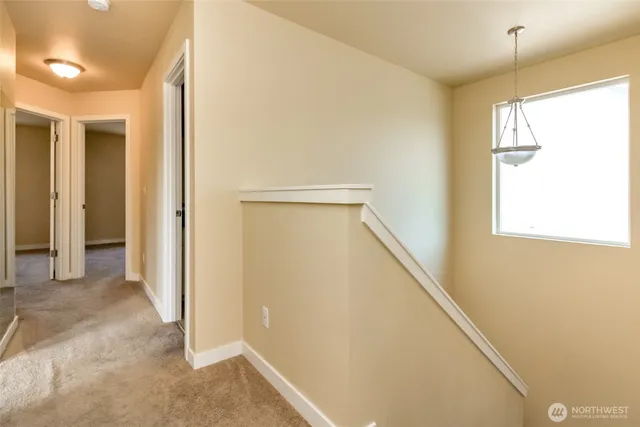 a view of hallway with window and wooden floor